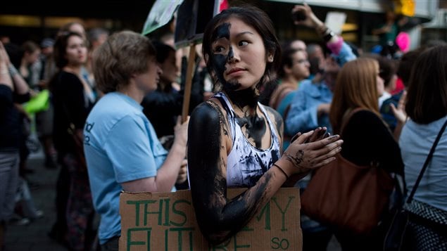 Jacqueline Lee-Tam wears face paint to simulate oil while attending a rally held to show opposition to the Enbridge Northern Gateway pipeline in Vancouver in June. She is of somewhat colour with jet-black hair tied in a braid.