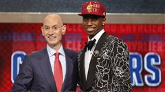 NBA Commissioner Adam Silver, left, congratulates Toronto's Andrew Wiggins, who was selected by the Cleveland Cavaliers as the number one pick in the 2014 NBA draft in June. Wiggins is just one of three Canadians slated to play with LeBron James, who returned to the Cleveland team last week. Silver, who is bald, is on the left of the photo, wearing a grey business suit and red tie. Wiggins is dressed in a red baseball hat and embroidered tuxedo. Both men have slightly forced smiles on their faces.