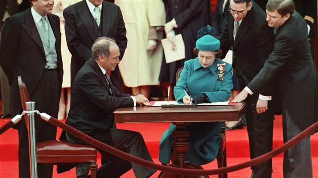 الملكة اليزابيت الثانية توقّع في اوتاوا  على استعادة الدستور في 17 نيسان ابريل 1982  تحت أنظار رئيس الحكومة في حينه بيار اليوت ترودو