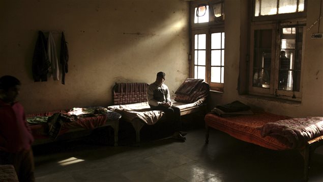 Canadian research provides hope that children like this visually impaired boy in India will be able to move out of the shadows. The photo shows a darkened room with a young man sitting on a bed. Sunlight is streaming in through a window to his left. He is looking to his right. Behind the young man is a gray wall. To his left is a couch decorated with an East Indian blanket.