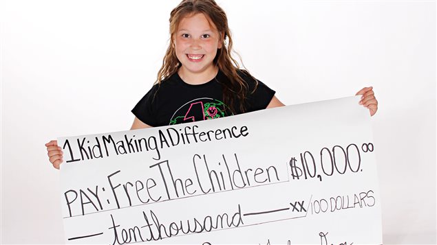 Taylor Devos muestra el cheque de la donación de 10.000 dólares a Free The Children.