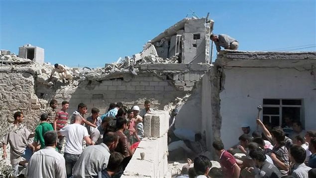 سوريون  في حلب أمام منازلهم التي دمّرها قصف القوات السورية للمدينة في 25 حزيران يونيو 2014