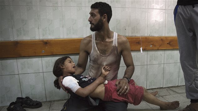 Un homme tient dans ses bras sa fille blessée lors du bombardement de l'école de l'ONU où ils s'étaient réfugiés.