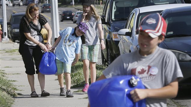 Mary Ellen Kavanaugh, and her children Abby, second from left, Grace and Owen, right, of Windsor, help carry water jugs to the water station set up at St. Peter's Episcopal Church in Detroit yesterday.