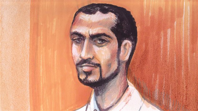 Omar Khadr as he looked in in an Edmonton courtroom, Sept. 23, 2013 in an artist's sketch. He has short dark hair and a thin, dark beard that comes down his cheeks and across his chin. All that connects with a dark moustache. The sketch is drawn from our right and he appears to be looking at the person drawing it. Behind him are the light brown walls of the courtroom.