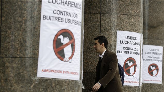 Un homme passe devant des affiches fixées à l'entrée du ministère de l'Économie en Argentine. On peut y lire : « Ensemble, nous allons lutter contre ces vautours usuriers ».