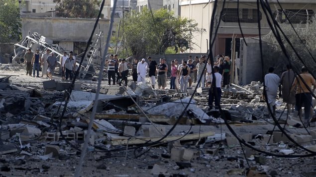 فلسطينيون  وسط ركام مصنع دمّره القصف الاسرائيلي في مدينة غزّة  في 31 تموز يوليو 2014