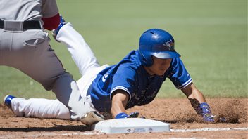 Jays infielder Munenori Kawasaki slides back to first base in a game last week in against Boston in Toronto. The Jays took six of seven from Boston over the past two weeks with Kawasaki providing much of the spark. Kawasaki, wearing a blue jersey and helmet and white pants, is reaching his his right hand and is clearly safe.