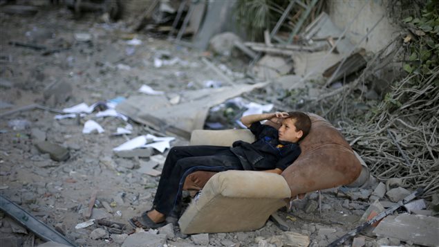 Un enfant assis parmi les décombres de sa maison dans la bande de Gaza.