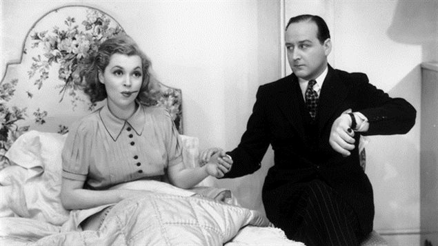 An editorial in the Canadian Medical Association Journal says it's time for doctors to evolve in the information they share with patients. We see a movie shot from the 1930s with a middle-aged doctor at the right of the picture, wearing a dark pin-stripped suit and matted down hair parted on the left. He is holding the wrist and taking the pulse of a younger woman, who is sitting up in her bed with a thermometer in her mouth. Surrounded by pillows, she has ash-blond hair and a look of forbearing on her face. 