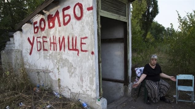 Une dame attend à l'entrée d'un abri anti-bombes en Ukraine. 