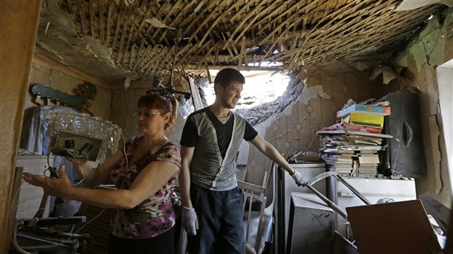 Deux résidents de Donetsk inspectent leur logement, touché par un obus. 