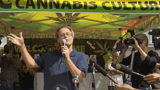 Marijuana advocate Marc Emery addresses well wishers in Vancouver Sunday. He says his main goal is to support wife Jodie's candidacy for the Liberal Party in Vancouver East. Wearing a dark blue polo shirt, Mr. Emery has a microphone in his left hand and is gesturing with his right hand. He stands below a green sign with dark green lettering that says "Cannabis Culture."