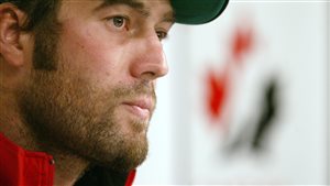 Todd Bertuzzi speaks to the media on the first day of training camp for the Canadian Men's Olympic Hockey Team in Vancouver in 2005. Bertuzzi is shown in right profile from the neck up. He is wearing a baseball cap and has the beginnings of a beard. His eyes are dark and his lips are slightly pursed.