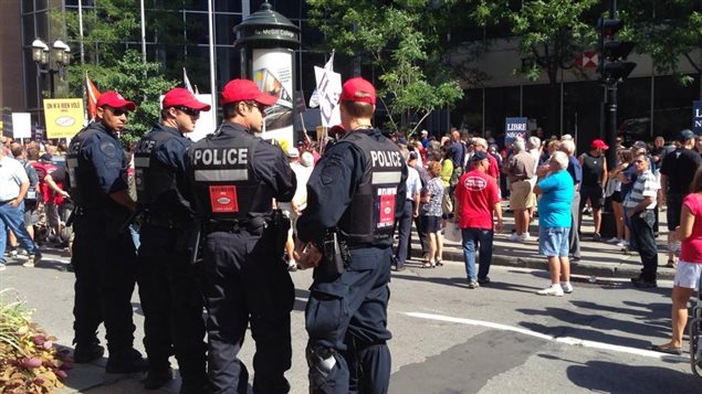 Agentes del Servicio de Policía de la Ciudad de Montreal vigilan la manifestación contra el proyecto de ley 3 frente a la oficina del primer ministro provincial Philipe Couillard. Dato curioso: los cuadros rojos que portan los policías son calcomanías contra la misma ley.