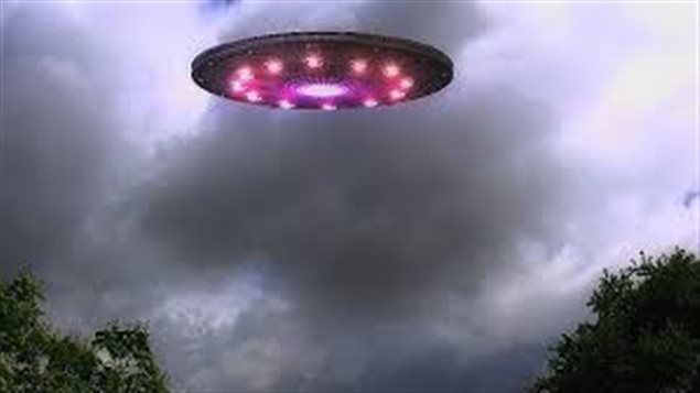 What is this anyway? Pretty unexplainable, eh? Looking up into the near sky we see a saucer-shaped red object filled with lights against a clouded evening sky.