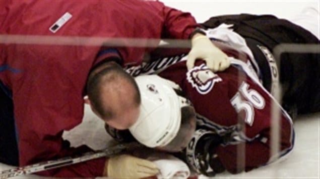Nine advocacy groups are calling for a unified approach to deal with concussions.  We see a hockey player (Steve Moore) face down on the ice with a trainer leaning over him. The trainer's head is right abreast of the player's white helmet.