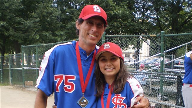 Eric Laferrière and his daughter Evelyn celebrate after their Quebec championship win earlier this month. They have their arms around each other as they both wear large smiles in their blue and white uniforms with cardinal red hats.