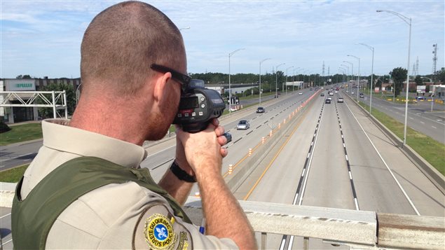 Un policier de la Sûreté du Québec utilise un radar pour vérifier la vitesse des automobilistes.