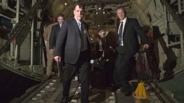 Foreign Affairs Minister John Baird, left, disembarks from a Canadian Forces Hercules relief flight as he arrives in Irbil, Iraq, on Wednesday. We see three men, all dressed in dark grey suits, coming down a gangplank with the innards of the Hercules behind them. Mr. Baird is centre left.