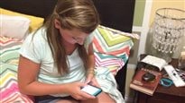 Social media is not helping in the fight to help young people with eating disorders. We see a young girl (perhaps 12 years old) sitting on her bed in a white tee-shirt very focused on her smartphone.