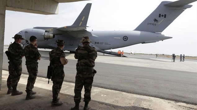 "Several dozen" Canadian military advisors are headed to Iraq for at least 30 days to counter the ISIL threat in the region. We see four Canadian soldiers in their camouflage brown uniforms standing side-by-side at a military air strip where a large transport plane stands at the ready on the runway.