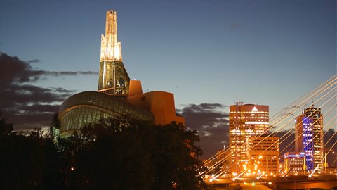 Le Musée canadien pour les droits de la personne (à gauche) et une partie du centre-ville de Winnipeg (à droite). C'est le premier musée du monde entièrement officiellement consacré à la sensibilisation et à l'éducation en matière de droits de la personne. 