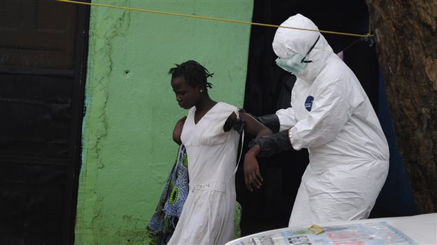 عامل صحة يرافق امرأة يُعتقد أنها مصابة بفيروس إيبولا إلى مستوصف نقال في مونروفيا، عاصمة ليبيريا، منتصف الشهر الحالي