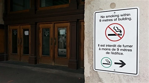 Une affiche sur laquelle on peut lire « Il est interdit de fumer à moins de neuf mètres de l'édifice » est photographiée devant le Centre de conférences du gouvernement, à Ottawa (archives). 