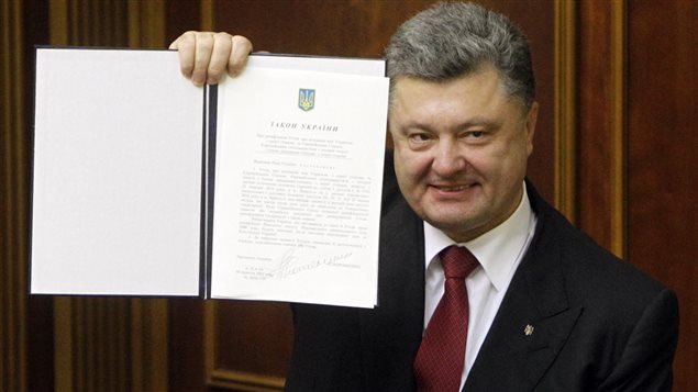 El presidente ucraniano Petro Porochenko muestra orgullosamente el texto del acuerdo adoptado por la UE y el parlamento de Ucrania.