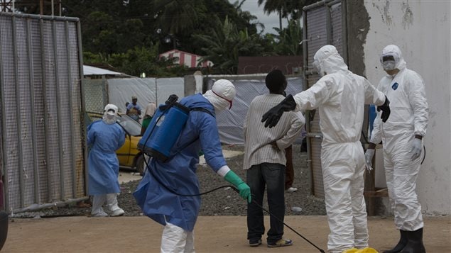 Des travailleurs humanitaires procèdent à la désinfection de leur équipement de protection au Liberia.