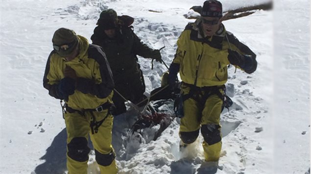 Des secouristes transportent le corps  d'un randonneur retoruvé dans la neige.