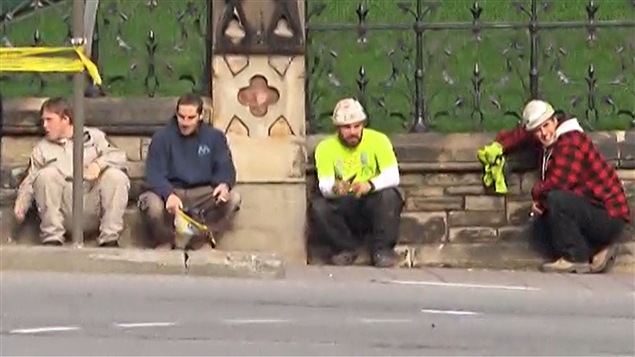 Des travailleurs de la construction ont trouv? refuge derri?re une cl?ture, devant la colline du Parlement, ? Ottawa.