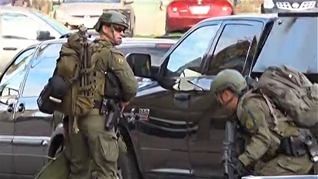Des membres des forces de l'ordre lourdement arm?s devant la colline du Parlement, ? Ottawa
