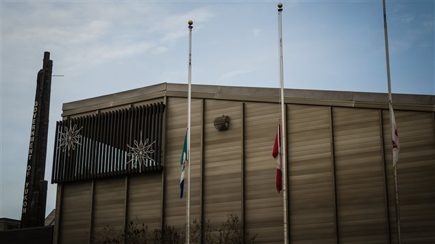 The Yukon Government building is shown from the outside were flags are being flown at half-mast. 