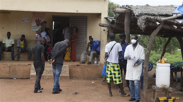 À Kouremale, un travailleur de la santé attend pour prendre la température des gens qui passent la frontière de la Guinée vers le Mali. 