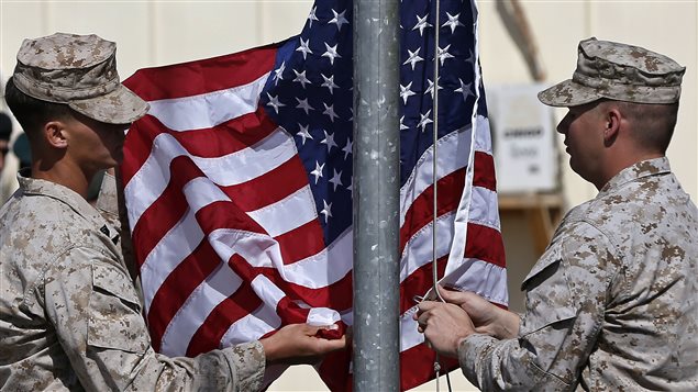 Des Marines américains abaissent et enroulent le drapeau américain pour la dernière fois avant de quitter l'Afghanistan.
