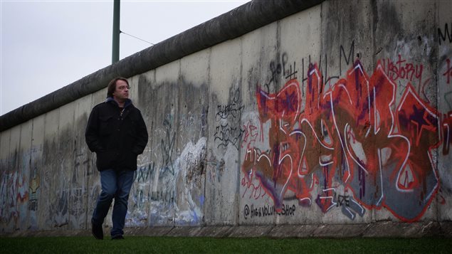 Adam Radomski devant un pan du mur de Berlin encore debout