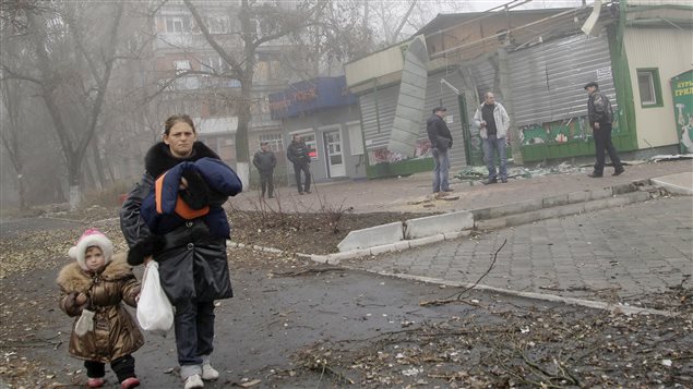 Une mère et sa fille marchent devant des bâtiments détruits par les bombes à Donetsk.