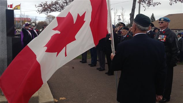 Un vétéran tient le drapeau du Canada.