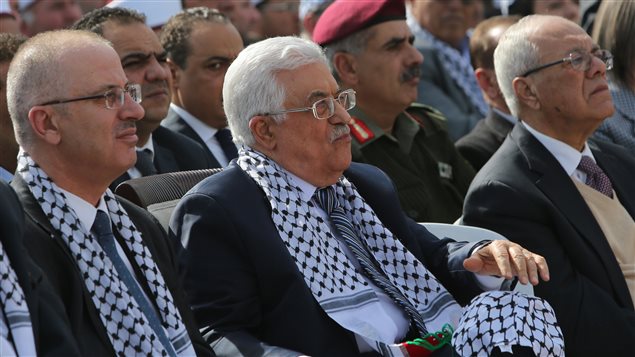 الرئيس الفلسطيني محمود عبّاس محاطا برئيس الحكومة رامي الحمدالله ( إلى اليسار) وأمين عام الرئاسة الفلسطينيّة طيّب عبد الرحيم يشاركون  في رام الله  في المهرجان العاشر لرحيل الرئيس عرفات في 10تشرين الثاني نوفمبر 2014