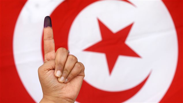 ناخبة تبرز إصبع السبابة الأيسر وقد تلون بالحبر الانتخابي الأزرق بعد إدلائها بصوتها في الدورة الأولى من الانتخابات الرئاسية التونسية أمس