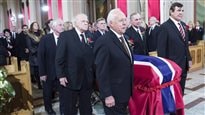 Pallbearers and former teammates carry the casket of Jean Beliveau into his funeral service on Wednesday. All (Bobby Rousseau, Jean-Guy Talbot, Phil Goyette, Yvan Cournoyer, Guy Lafleur and Serge Savard wear sombre expressions and dark suits. All, except Savard, have grey hair. The casket is draped in a red, white and blue Canadiens flag.