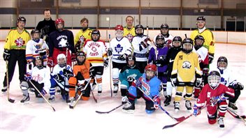 Canadian kids begin the pursuit of their NHL dream at a very early age. A tiny fraction every get there. We see a group of elementary school kids posing on the ice in their blue, red, white and yellow jerseys. Some are standing. Others are on one knee with their sticks in front.