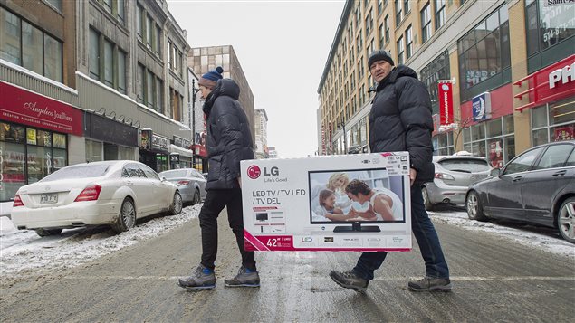 Two successful Boxing Day shoppers hit the streets last year in Montreal. About 40 per cent of Canadians were expected to be in stores on Friday. We see two men, who appear to be father and son (the son is on the left in the photo), walking across a slushy Ste. Catherine Street carrying a box that contains a large-screen television. They are dressed in warm winter coats and toques and do not appear especially joy filled.