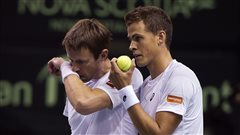 Daniel Nestor, left, and Vasek Pospisil discuss their plan as they play Colombia in Davis Cup doubles action in September. Pospisil made great progress last season in doubles, winning Wimbledon with partner Jack Sock. Both are dressed in whites. Nestor is wiping his face with his left arm while Pospisil's left arm is raised to his face. He is holding a yellow tennis ball. Both have short blond-brown hair. 