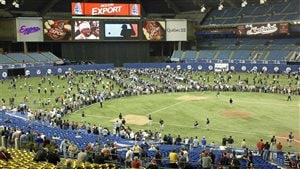 Fans roam the outfield at Olympic Stadium prior to the final Montreal Expos home game on Sept. 29, 2004. Montreal baseball backers say big league baseball in the city is not dead, only dormant. It's a long shot from the third base side of the diamond. The green inner diamond is roped off as several hundred fans walk in the outfield. 