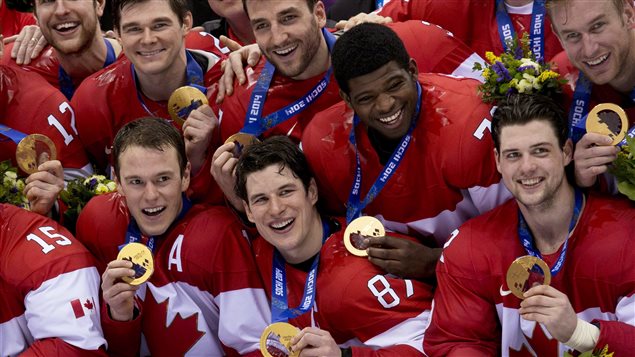 The men's hockey team flashes gold after their 3-0 victory over Sweden in the final. The boys are all dressed in their red sweaters. In the centre is captain Sidney Crosby.Above his left shoulder in P.K. Subban. Everyone has a giant smile on his face.. 