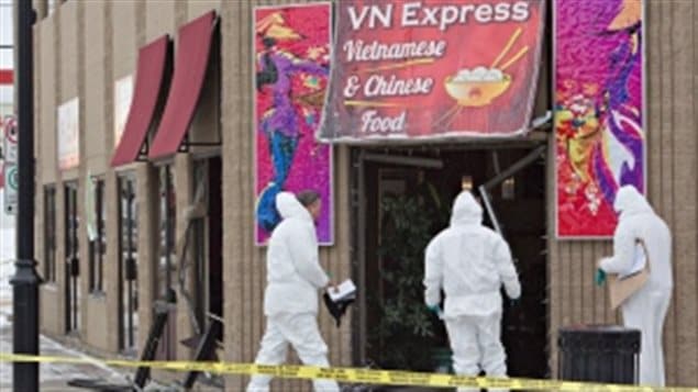 Police Tuesday investigate a Fort Saskatchewan, Alberta restaurant, said to be related to multiple deaths that occurred in a north Edmonton home. The Vietnamese resturant has a large red awning over the front door. Three police officers dressed in white hazmat suits are seen behind a yellow police line strip.
