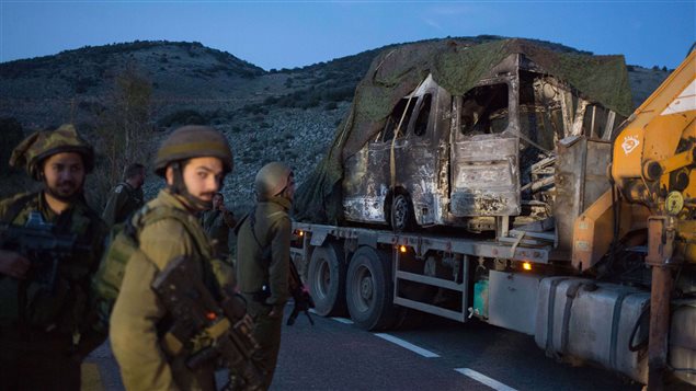 جندي إسرائيلي بالقرب من آليّة محترقة في قرية الغجر في 28 كانون الأوّل يناير 2015